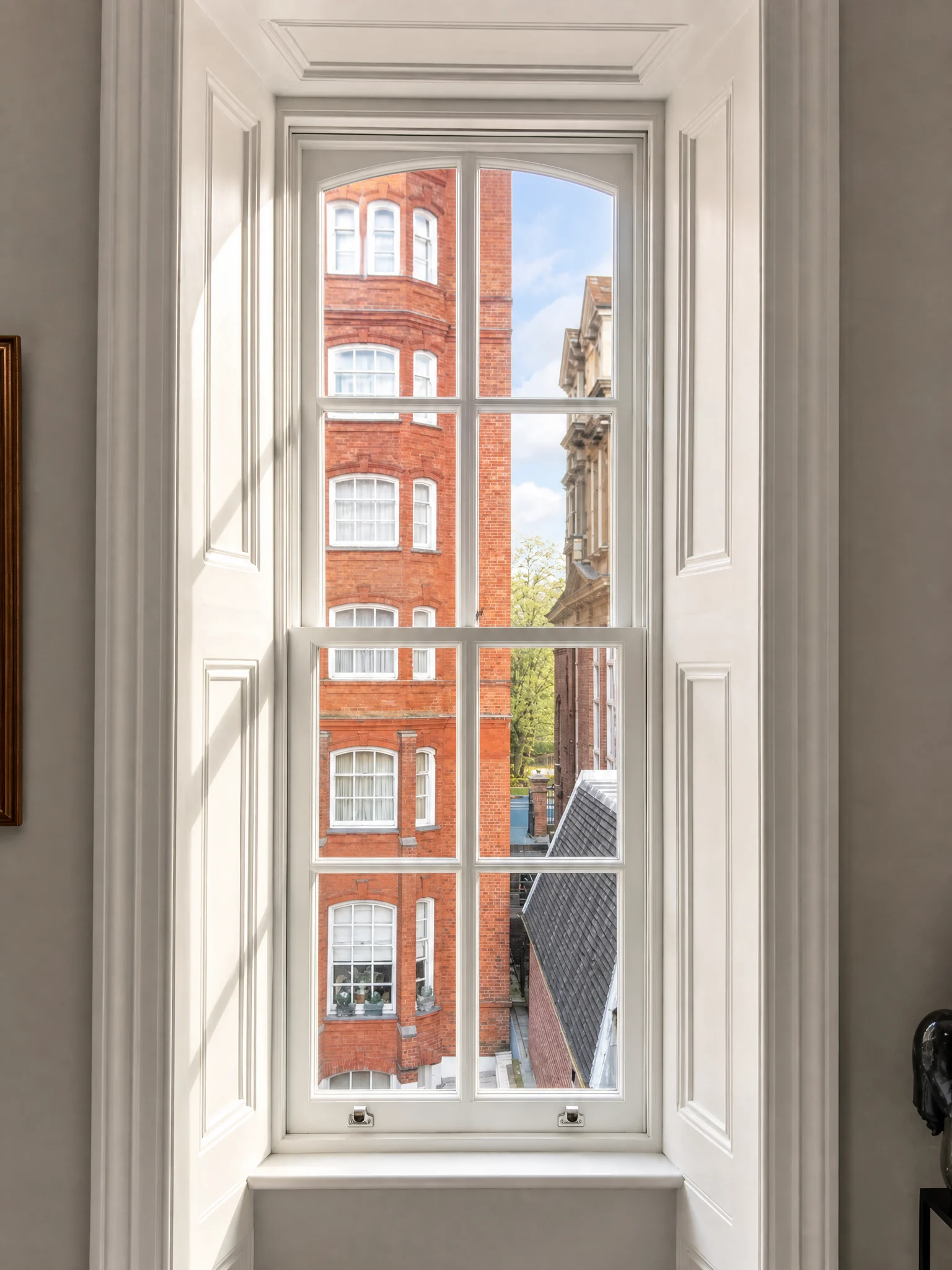 Tall restored sash window with panelled shutters